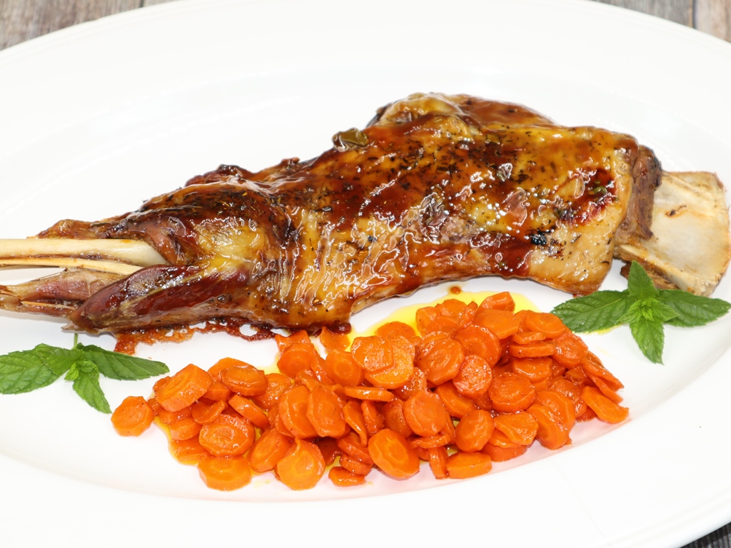 una-paletilla-de-cordero-crujiente-y-brillante-sobre-un-plato-blanco-acompanada-de-zanahorias-caramelizadas-y-hierbabuena